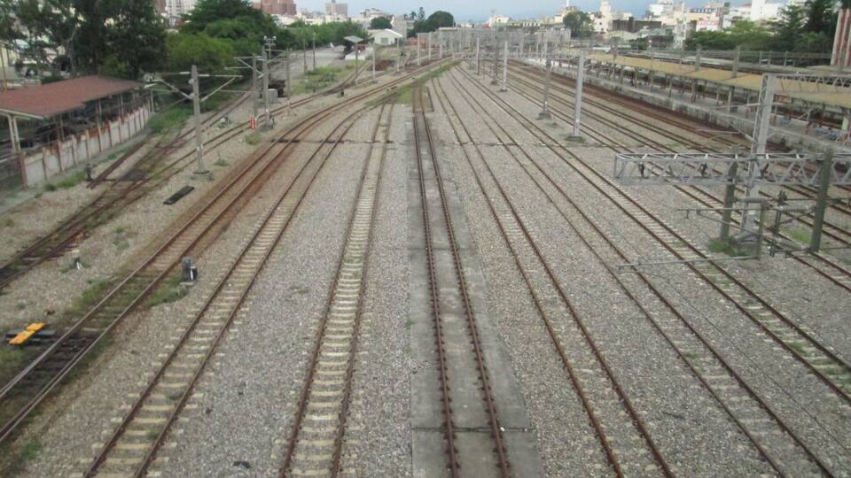 A railway yard with multiple tracks and overhead electrical lines.