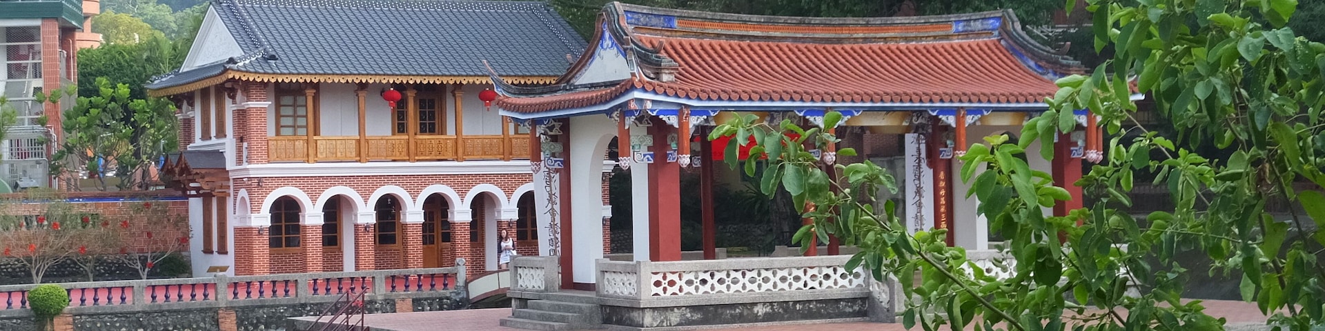 Um edifício tradicional chinês com telhado ladrilhado e um pequeno pavilhão com grade.