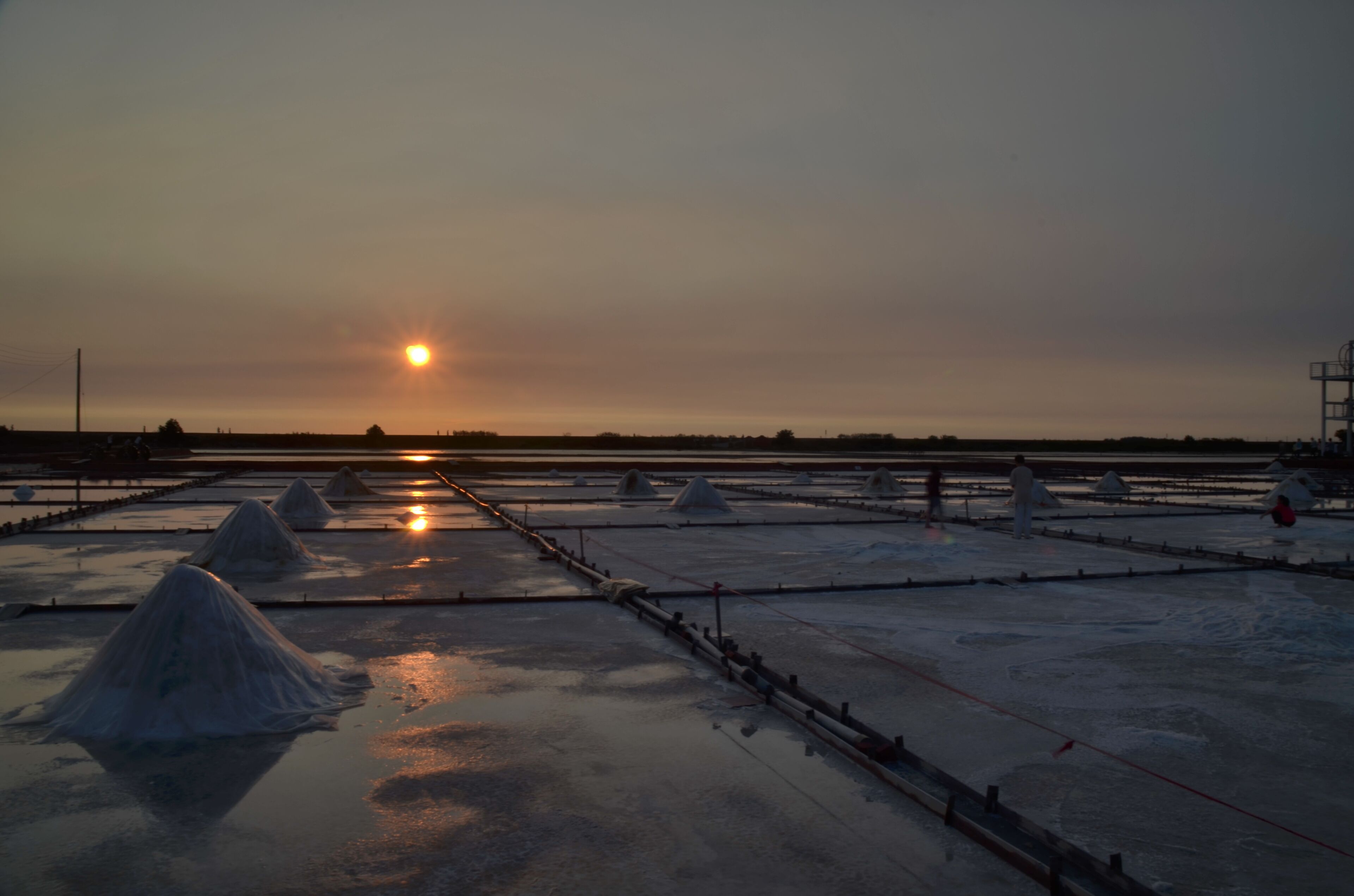 A salt flat at sunset with the sun low on the horizon.