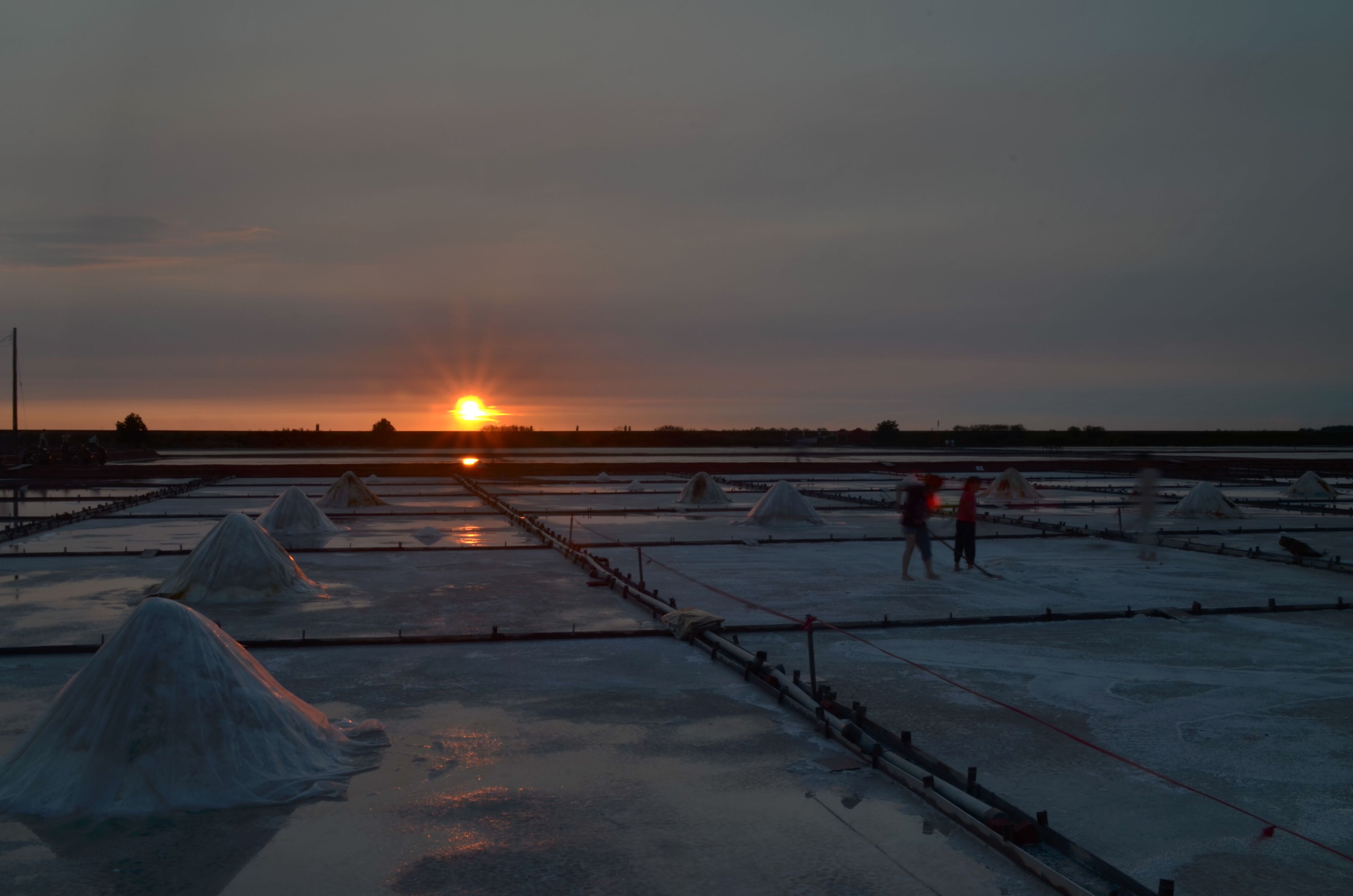 A salt flat at sunset with the sun low on the horizon.