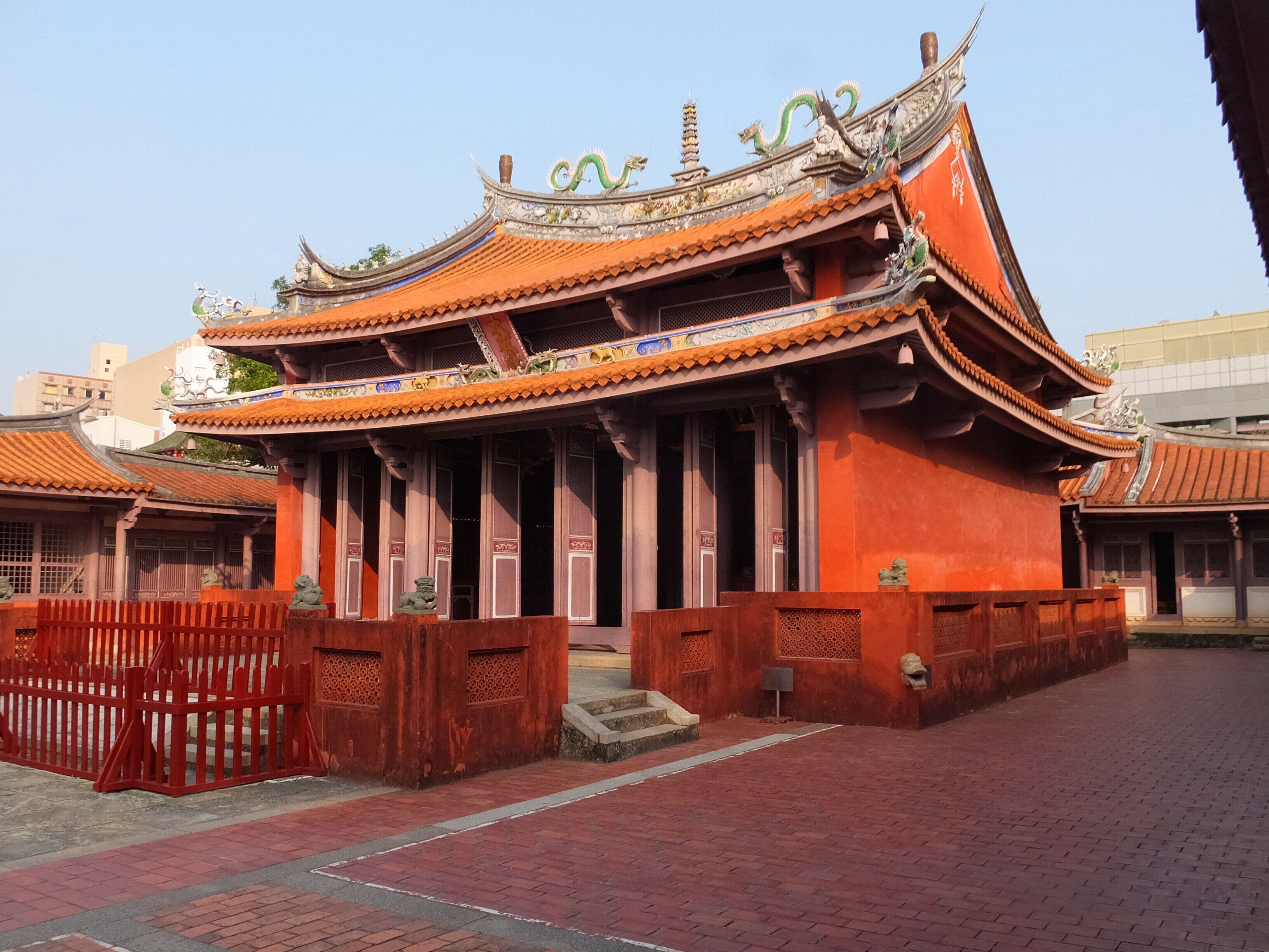 Ein traditionelles chinesisches Gebäude mit aufwendiger Architektur, darunter ein grüner Drache auf dem Dach und rote Wände.