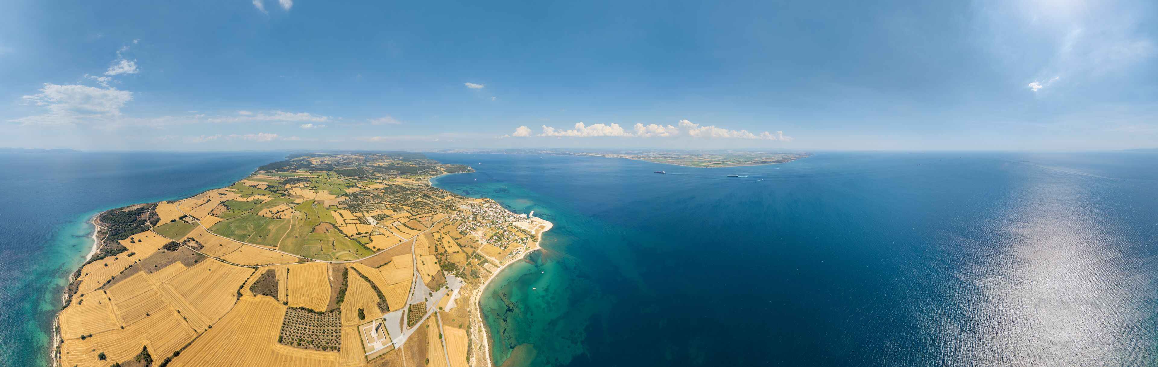 An aerial view of a coastal landscape with fields, a beach, and a distant island.