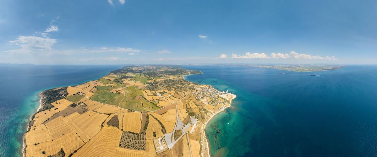 An aerial view of a coastal landscape with fields, a beach, and a distant island.