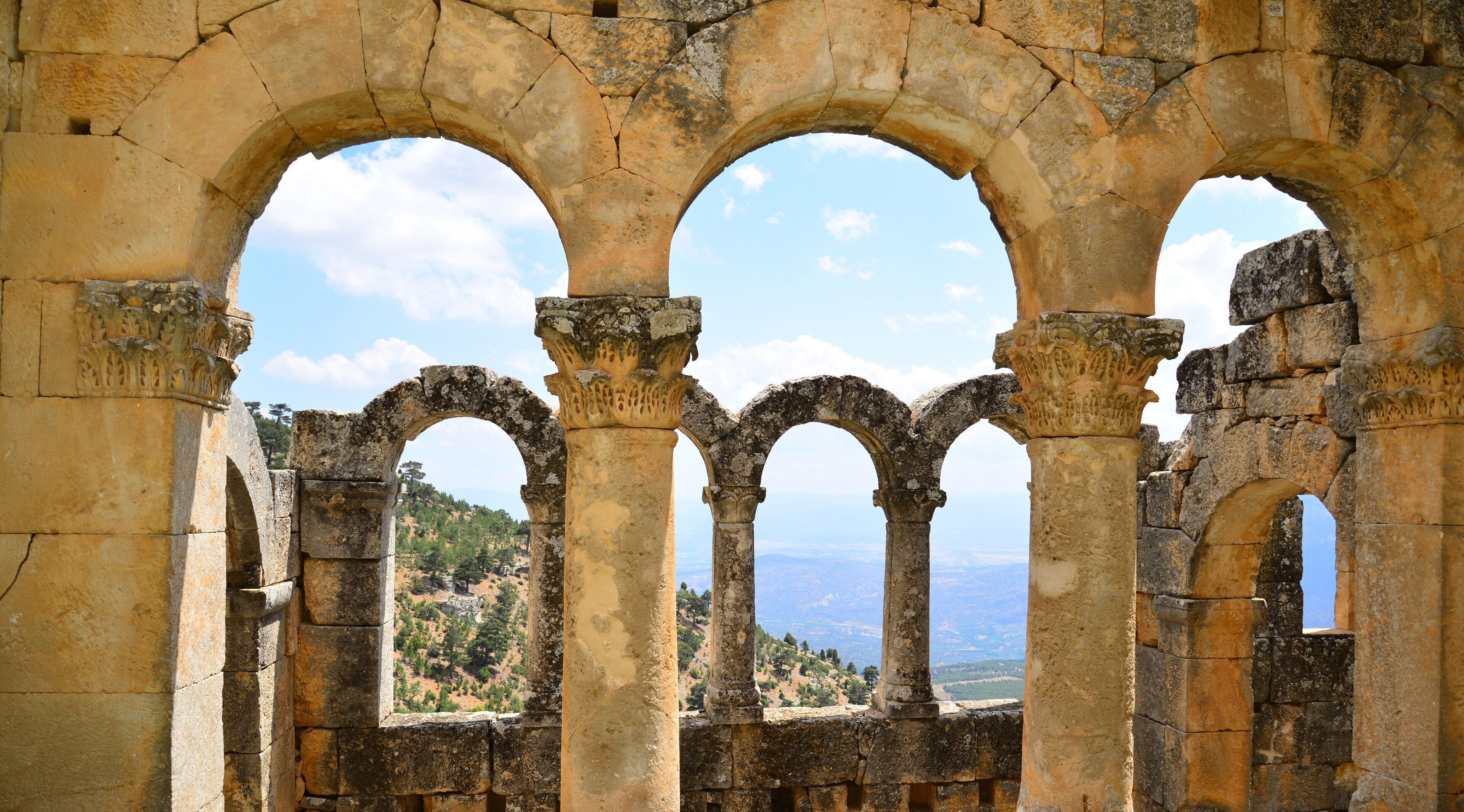 Ancient stone arches with a view of a hilly landscape.