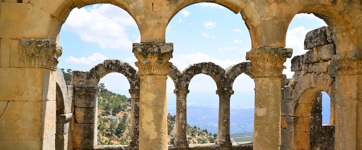 Ancient stone arches with a view of a hilly landscape.