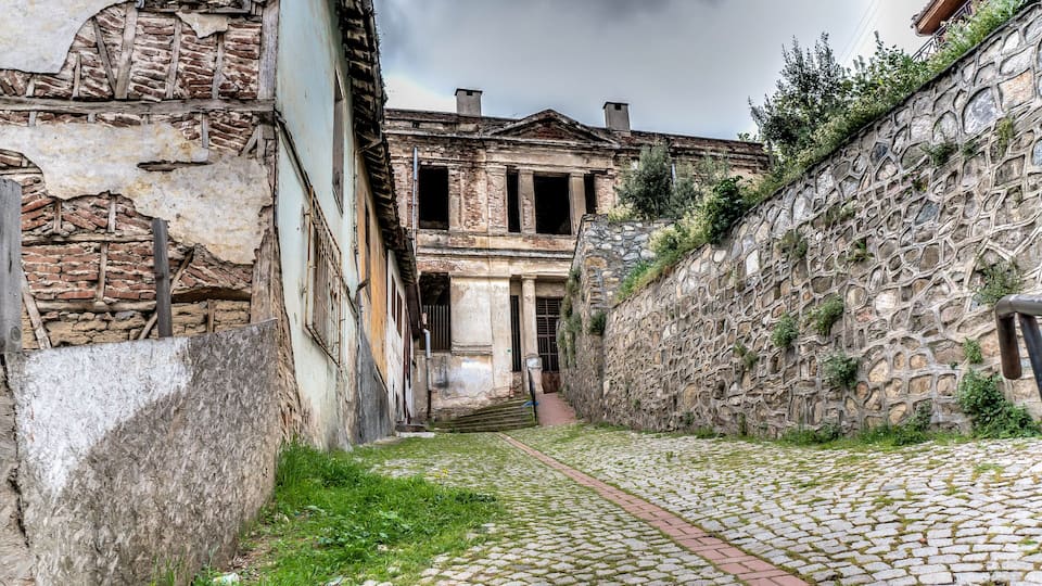 A cobblestone alleyway with a historic building featuring stone walls and a brick facade.