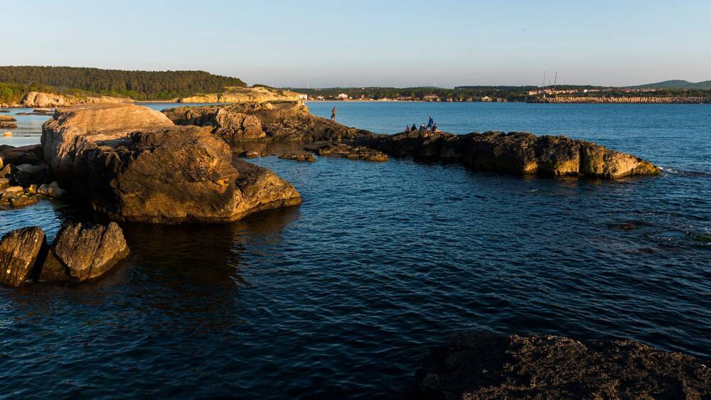 A rocky shoreline with large boulders and calm water.