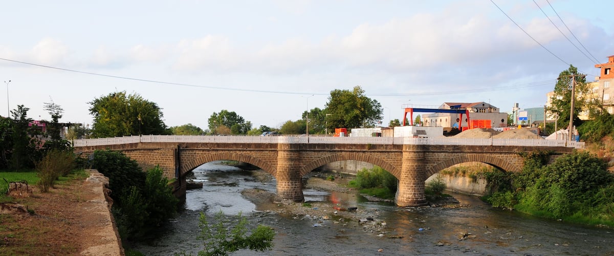 A stone bridge over a river with a paved path on one side.