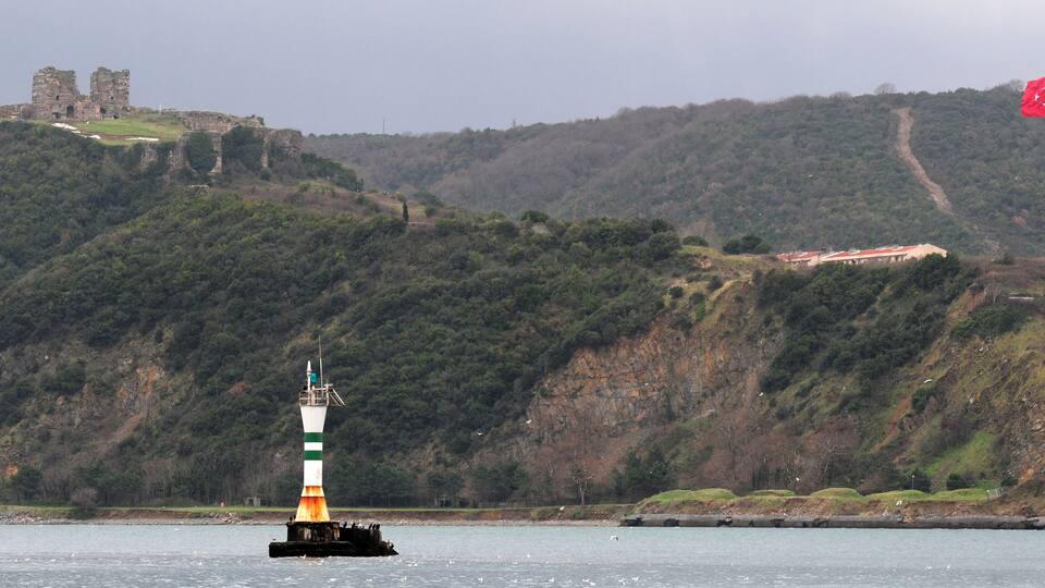 A lighthouse on a buoy, a castle on a hill, and a flag on a pole.