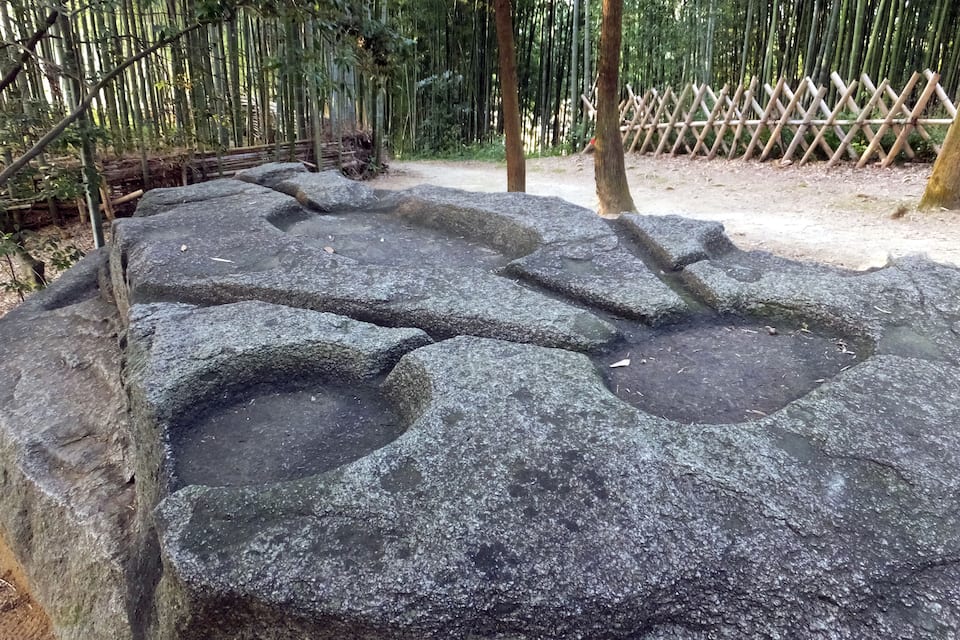Metsäisellä alueella sijaitseva kivirakennelma, jossa on pyöreitä syvennyksiä.