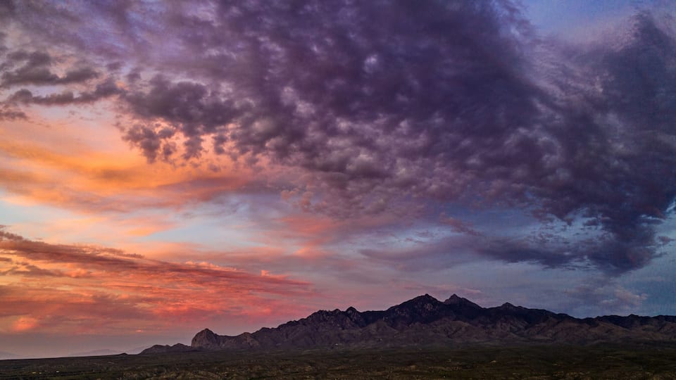 A mountain range under a colorful sky.