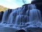 Ein mehrstufiger Wasserfall stürzt über Felsen.