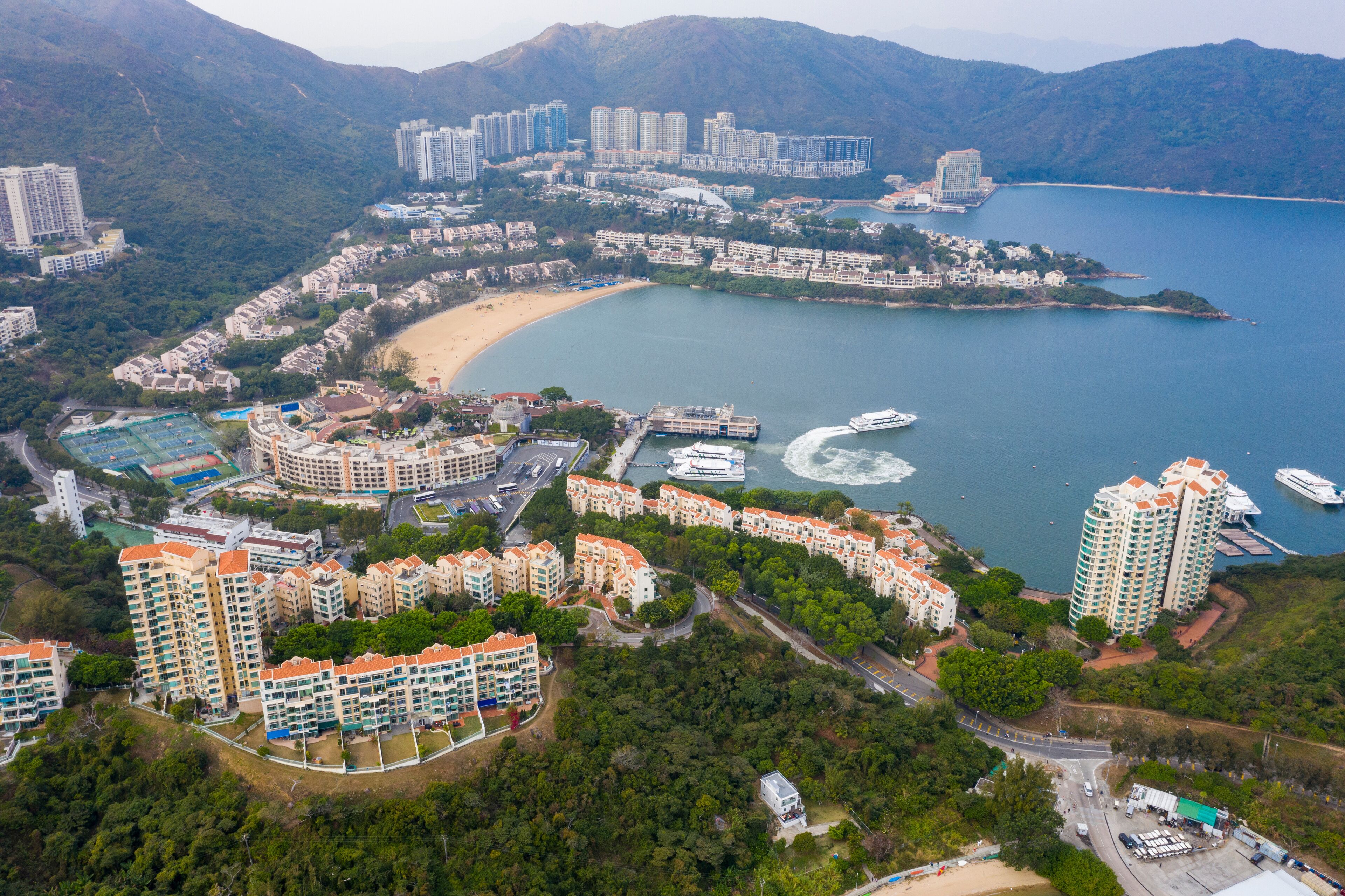 A coastal residential area with high-rise buildings, a beach, and a marina.