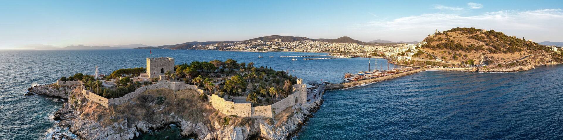 Kusadasi, Aydin, Turkey. Guvercinada Island (Pigeon Island) and Guvercinada Castle with Kusadasi city background. Kusadasi is a popular tourist destination in Turkey. Drone shot.