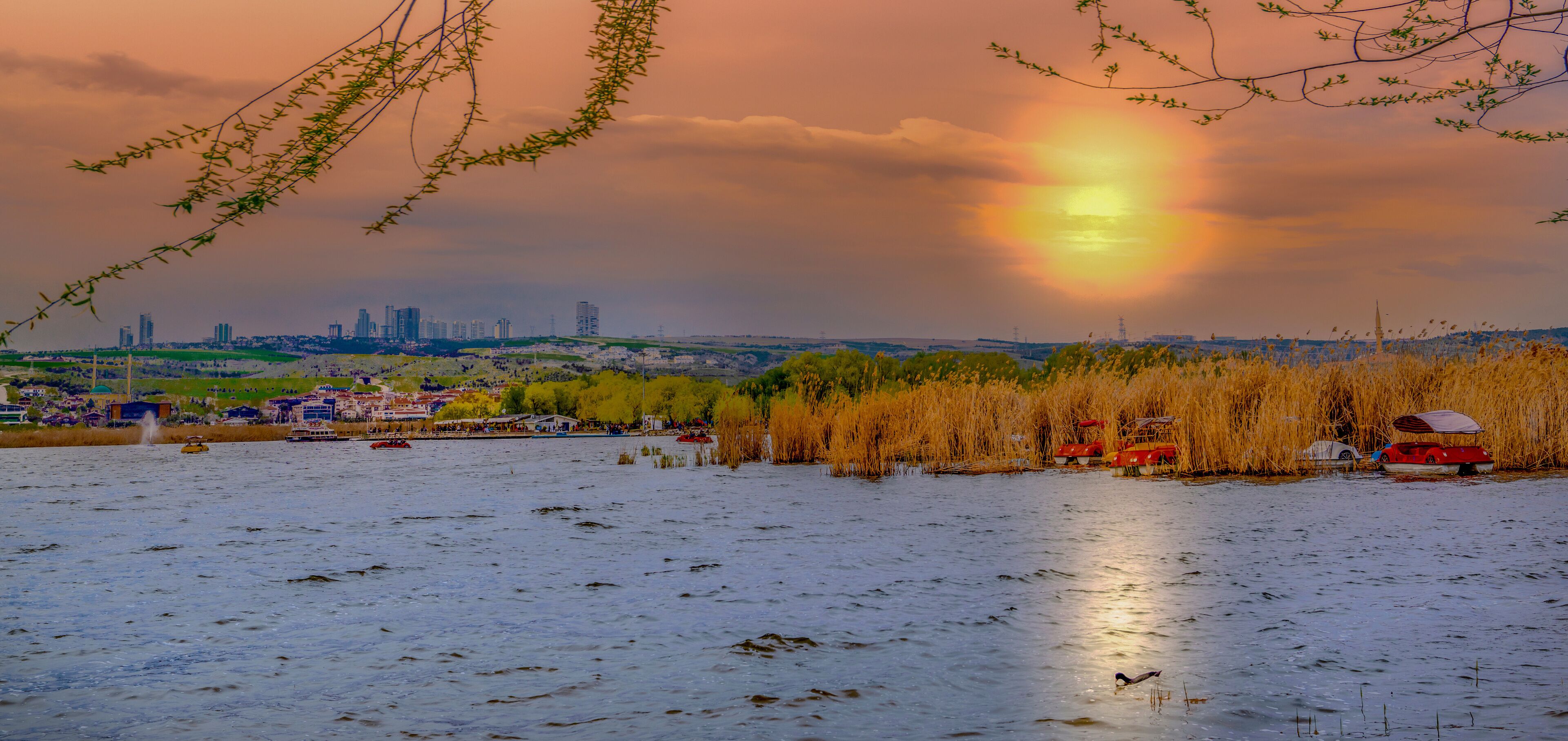 A sunset over a river with a city skyline in the background.