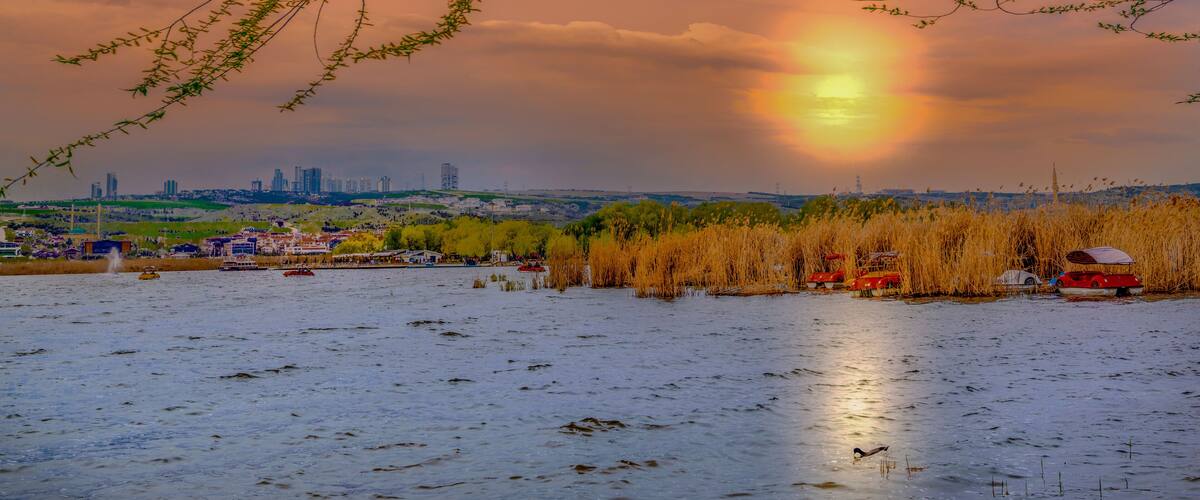 A sunset over a river with a city skyline in the background.