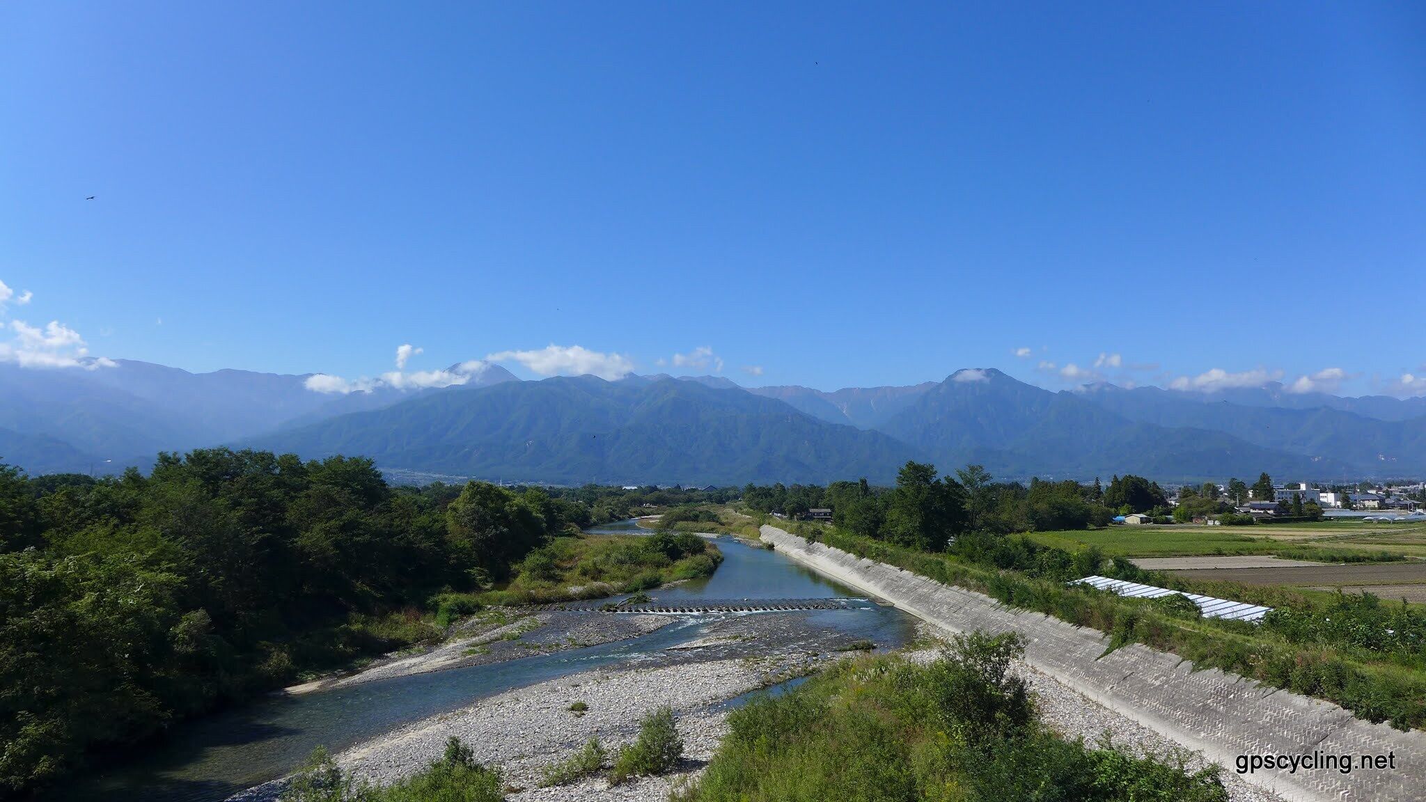 A river flowing through a valley with mountains in the background.