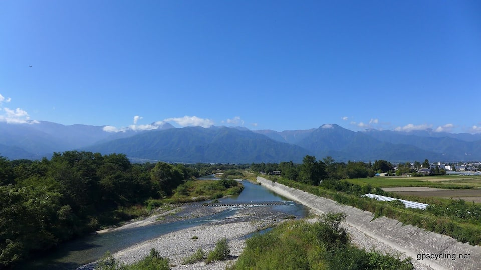 A river flowing through a valley with mountains in the background.