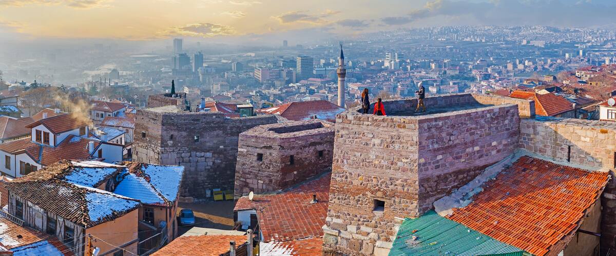 A historic cityscape with stone fortifications and traditional buildings.