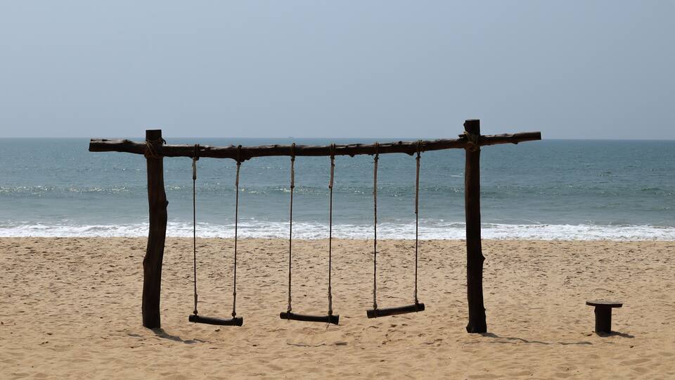 A beach with a wooden swing set.