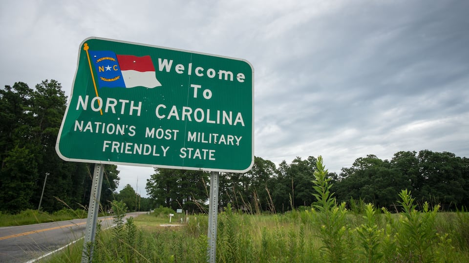 A road sign welcoming visitors to North Carolina, highlighting its military significance.