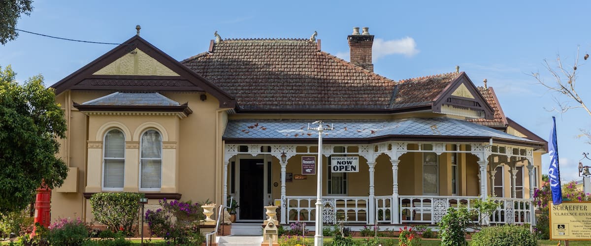 A historic building with a tiled roof, a porch, and a sign indicating a historical display.