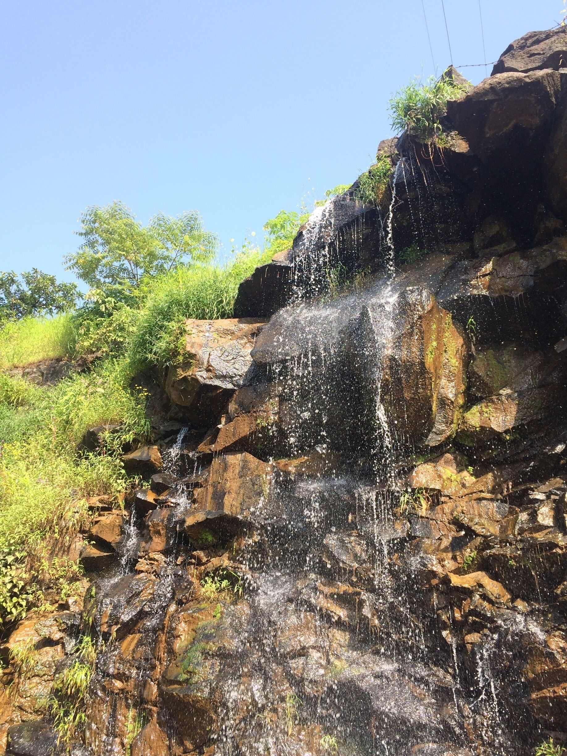 A waterfall cascading over rocky terrain with lush greenery around.