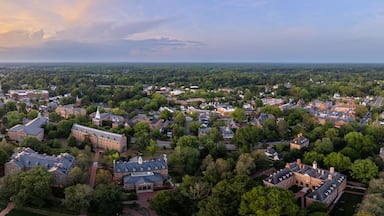 A university campus with historic buildings, green lawns, and a sunset in the background.