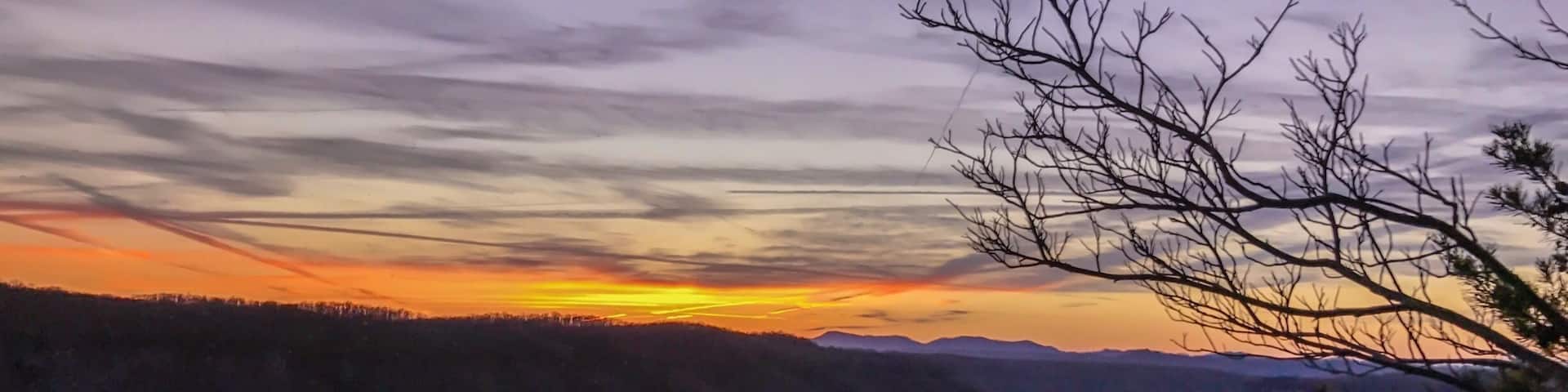 A sunset over a mountainous landscape with a river flowing through a valley.