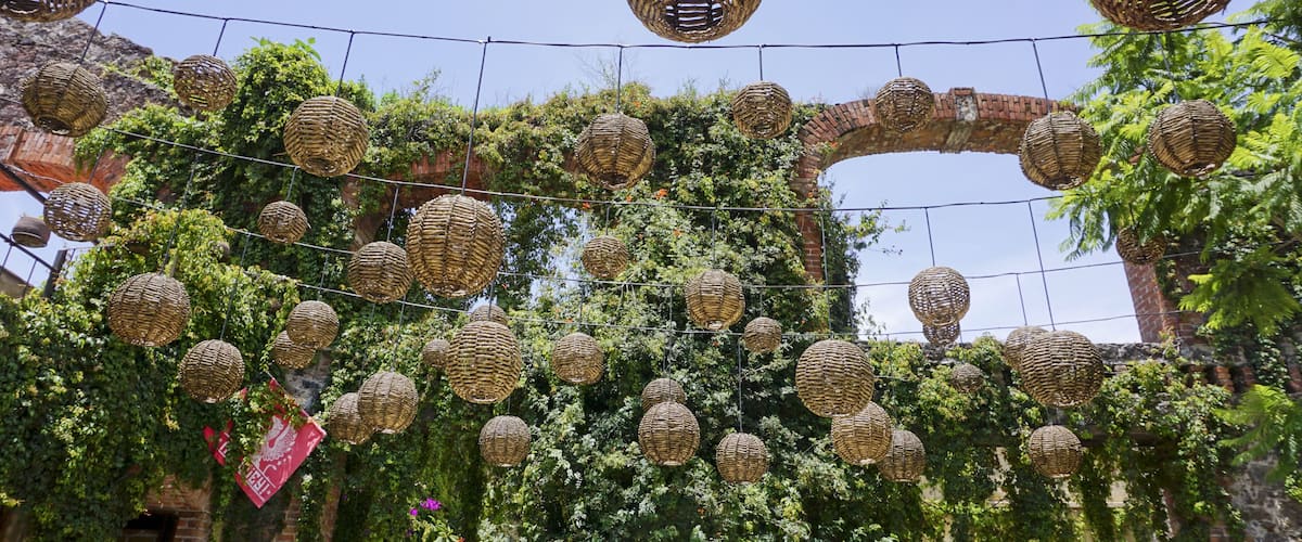 A garden with hanging wicker spheres and ivy-covered walls.