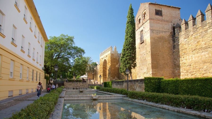 A historic stone wall with a moat and a building with yellow facades.