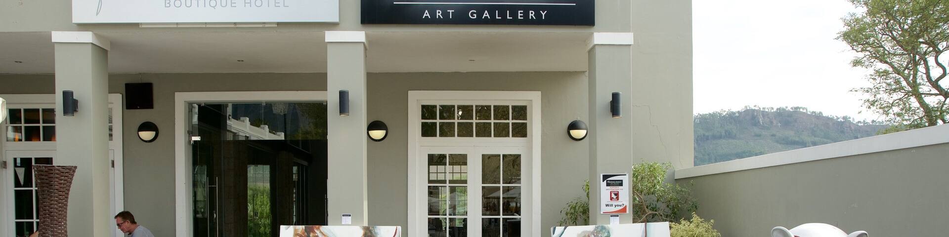 La entrada del Franschhoek Boutique Hotel y la Galería de Arte Senéchal-Senekal, con pinturas abstractas y una gran escultura de cerámica con forma de cerdo.