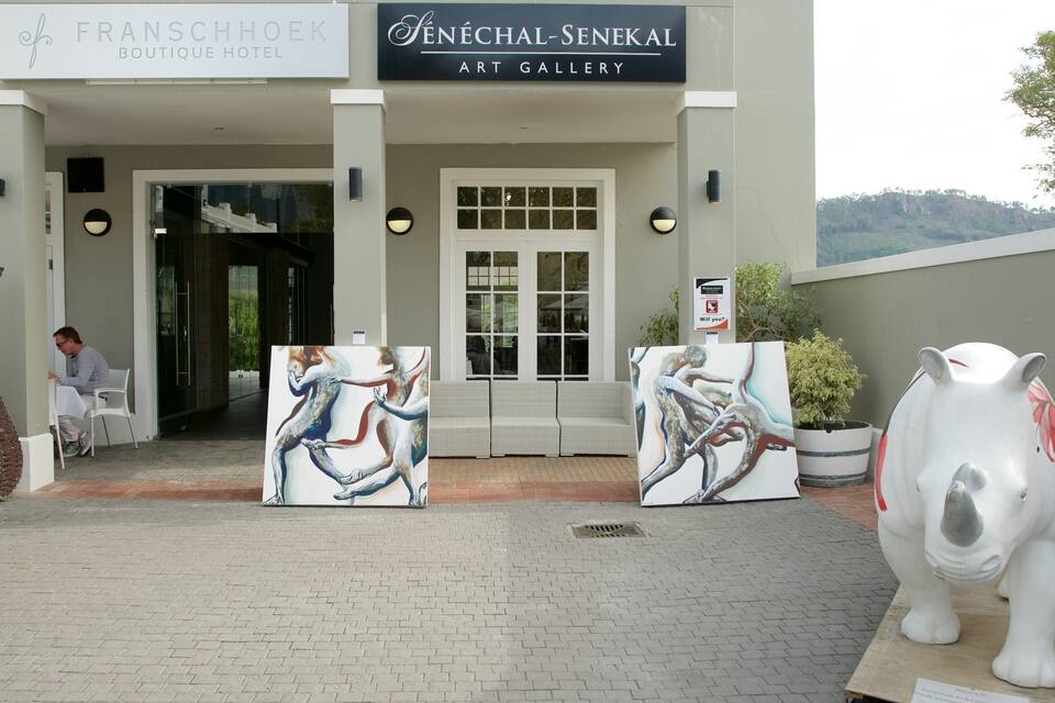 De ingang van het Franschhoek Boutique Hotel en de Senéchal-Senekal Kunstgalerie, met abstracte schilderijen en een grote keramieken varkensbeeldhouwkunst.