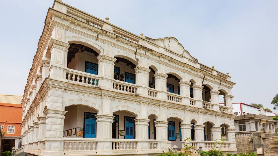 A historic building with white walls, blue doors, and multiple arches.