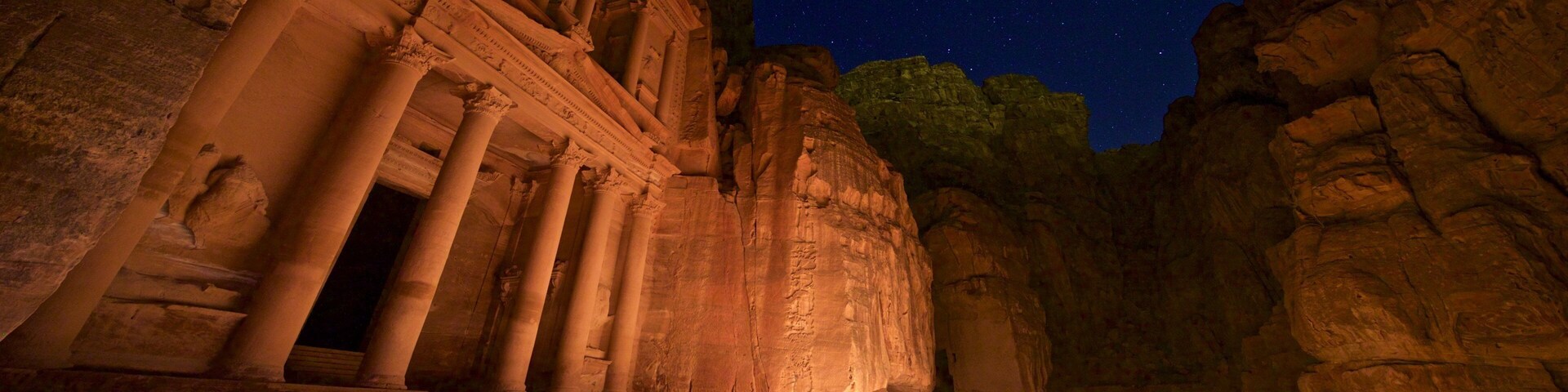 A night scene at Petra with illuminated candles and ancient rock-cut architecture.