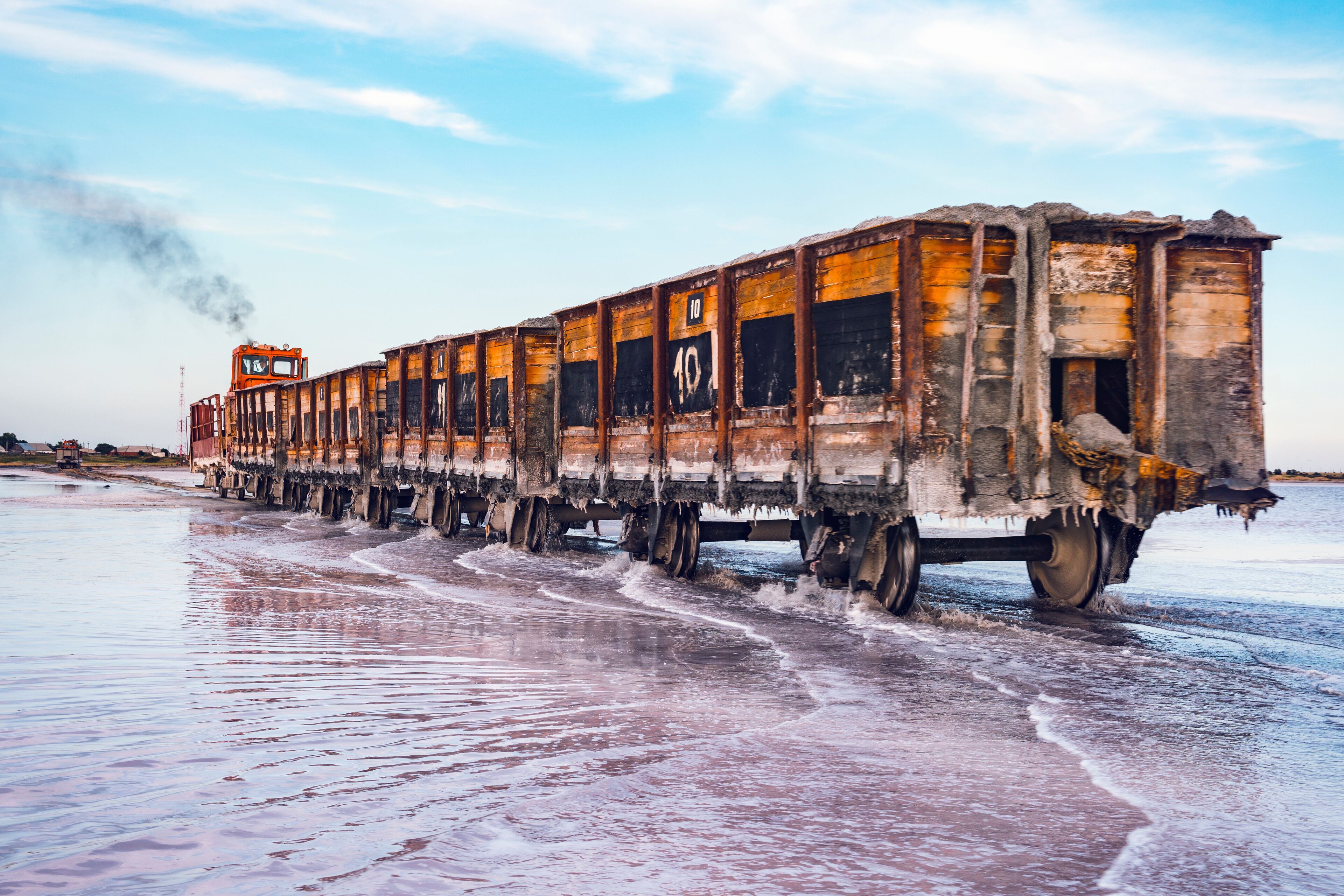 Awesome train rides on rail in the water with white salt on the background of beautiful blue sky.