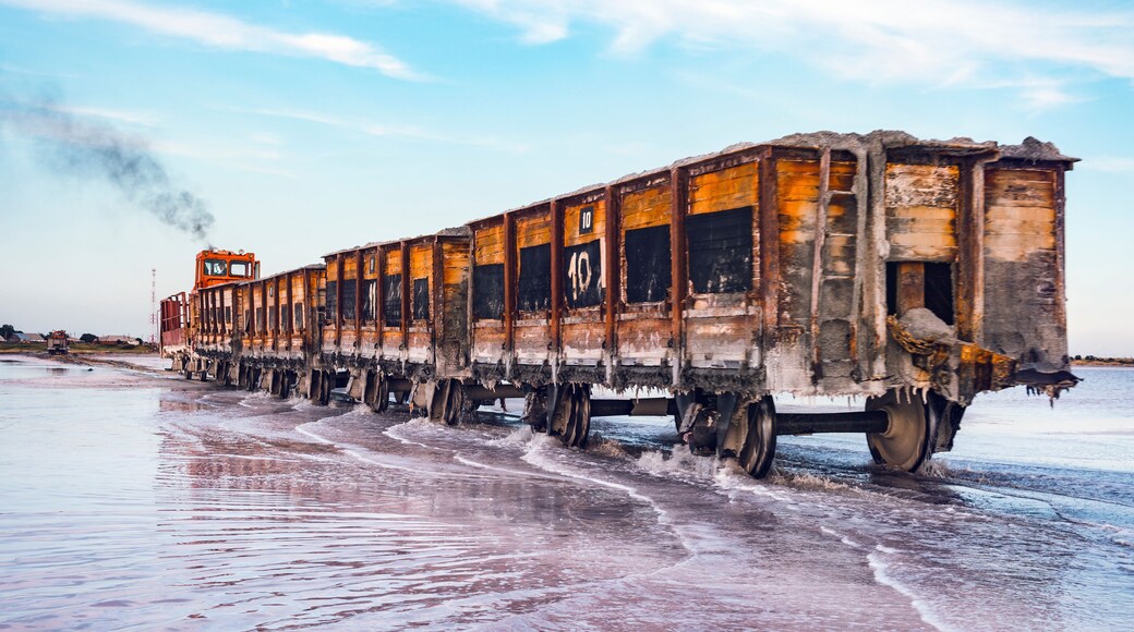 Awesome train rides on rail in the water with white salt on the background of beautiful blue sky.