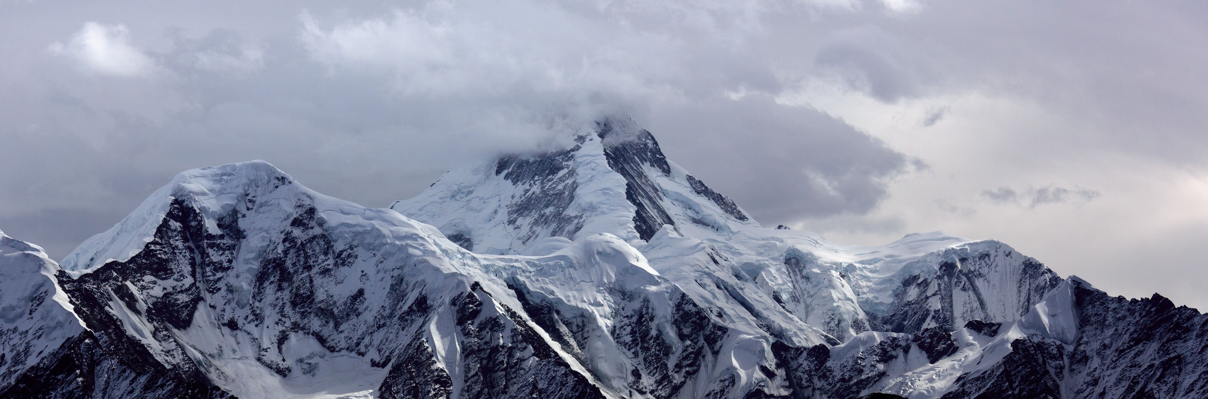 Minya Konka (Mount Gongga, Holy Tibetan Snow Mountain) - Gongga Shan in Sichuan Province, China. View from the west at Yaha Pass, summit shrouded in clouds. Highest Mountain in Sichuan Province China.