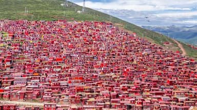 Uma povoação densamente construída numa encosta, com muitos edifícios vermelhos.