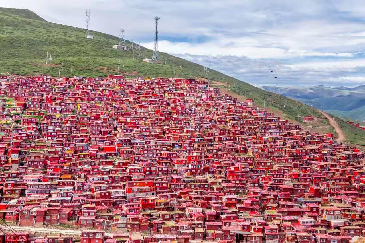 A densely packed hillside settlement with numerous red buildings.