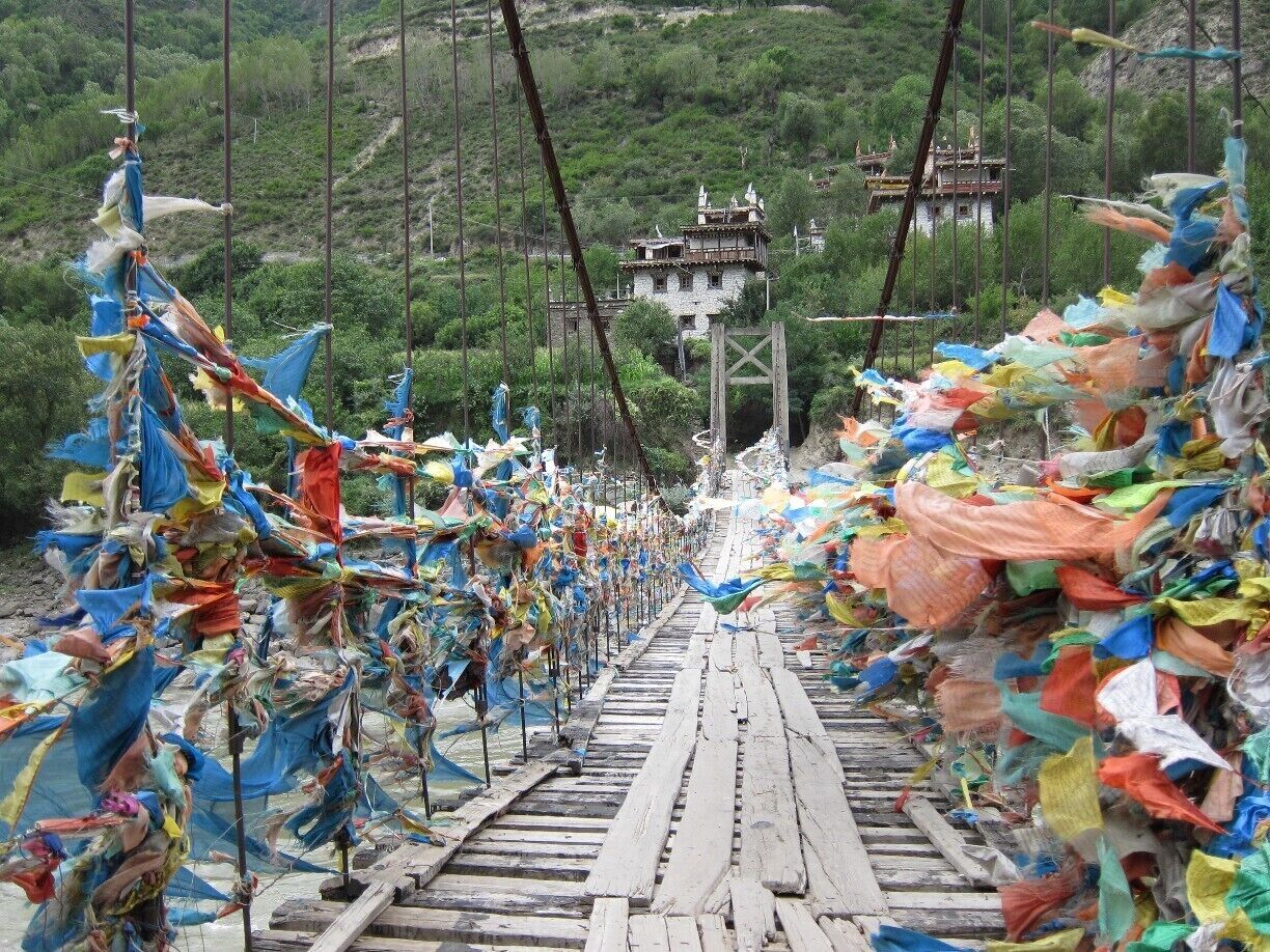 A suspension bridge adorned with colorful prayer flags.