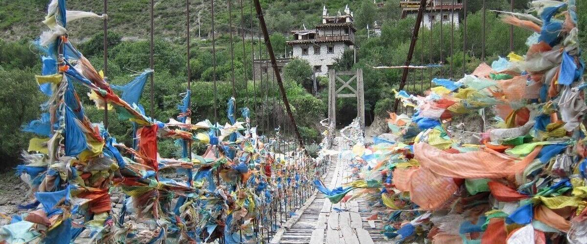 A suspension bridge adorned with colorful prayer flags.