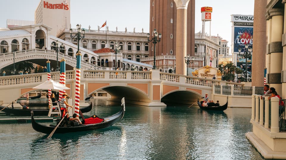 Gondolas on a canal in a city with historic architecture and casinos.