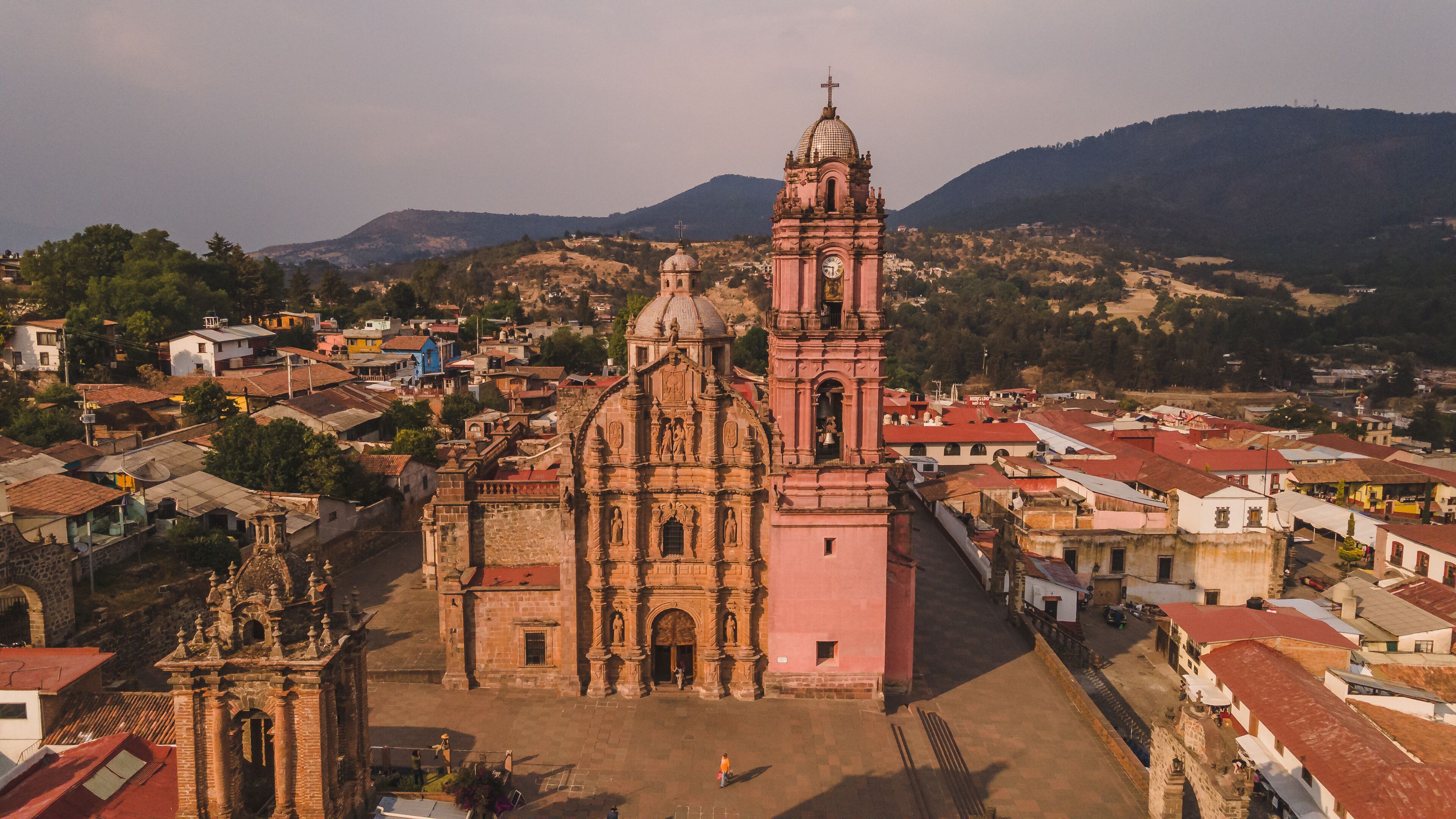 A historic church with a bell tower and a dome, surrounded by a town with red-roofed buildings.