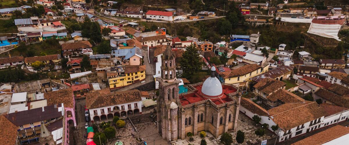 An aerial view of a historic town with a prominent church, narrow streets, and colorful buildings.