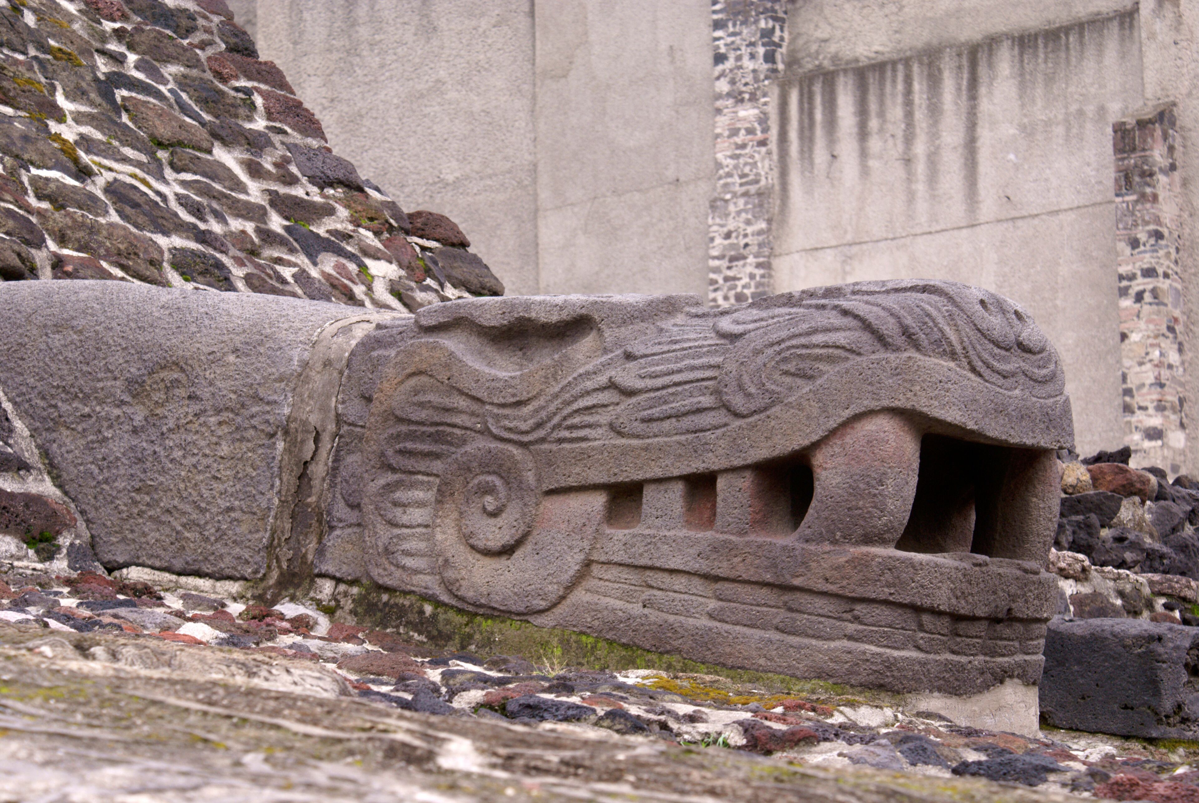 A stone carving of a mythical creature with a spiral design and a mouth.