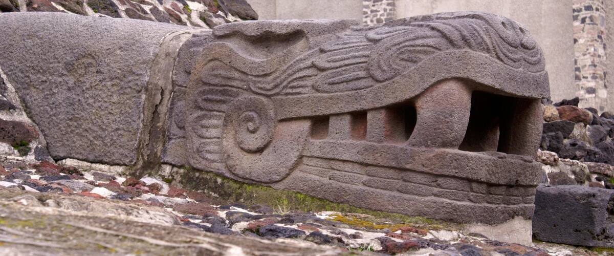 A stone carving of a mythical creature with a spiral design and a mouth.