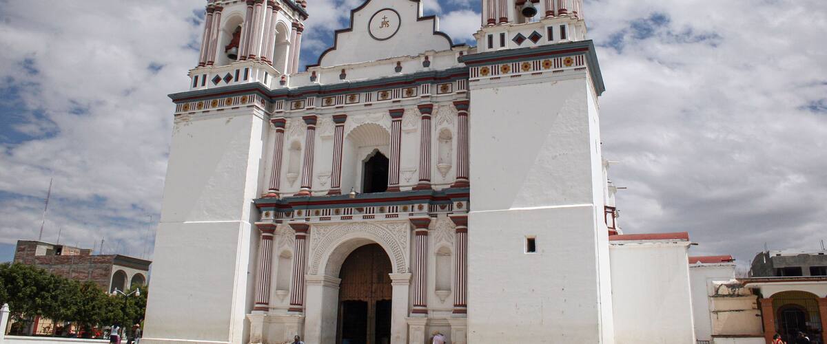 A large white church with two bell towers and a clock.