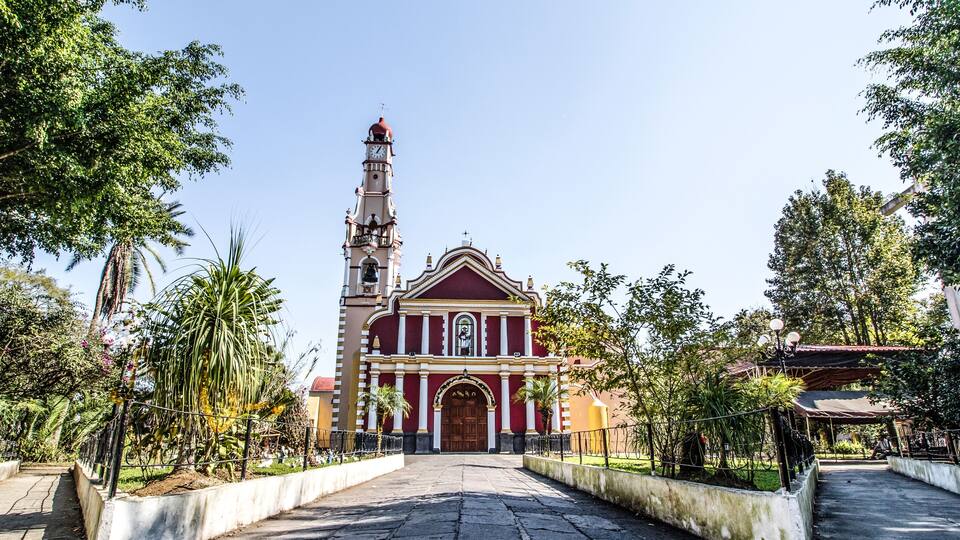 A church with a tall bell tower and a red facade.