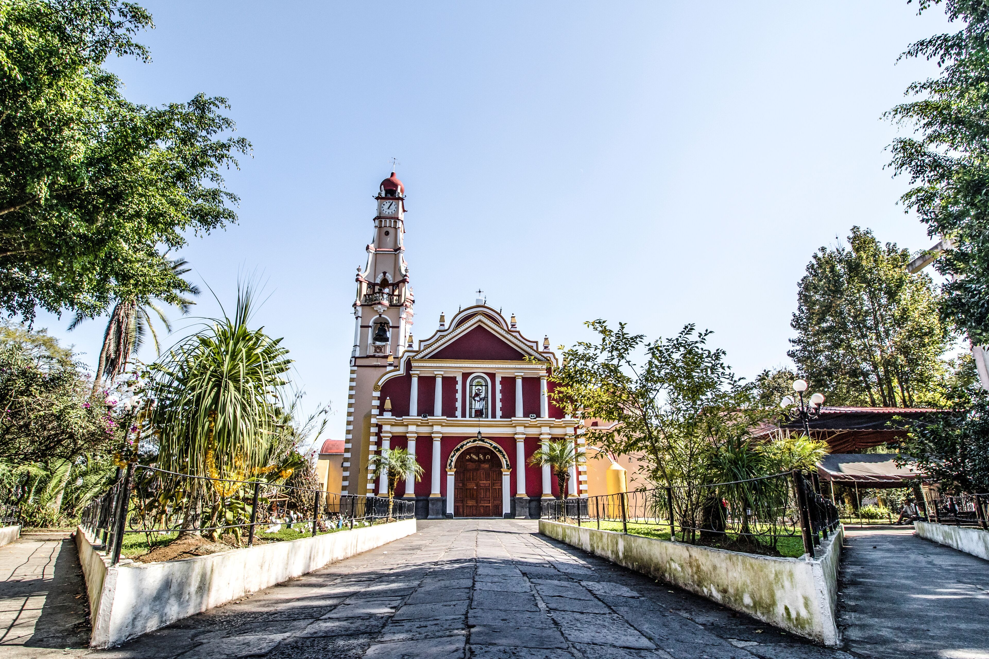 A church with a tall bell tower and a red facade.